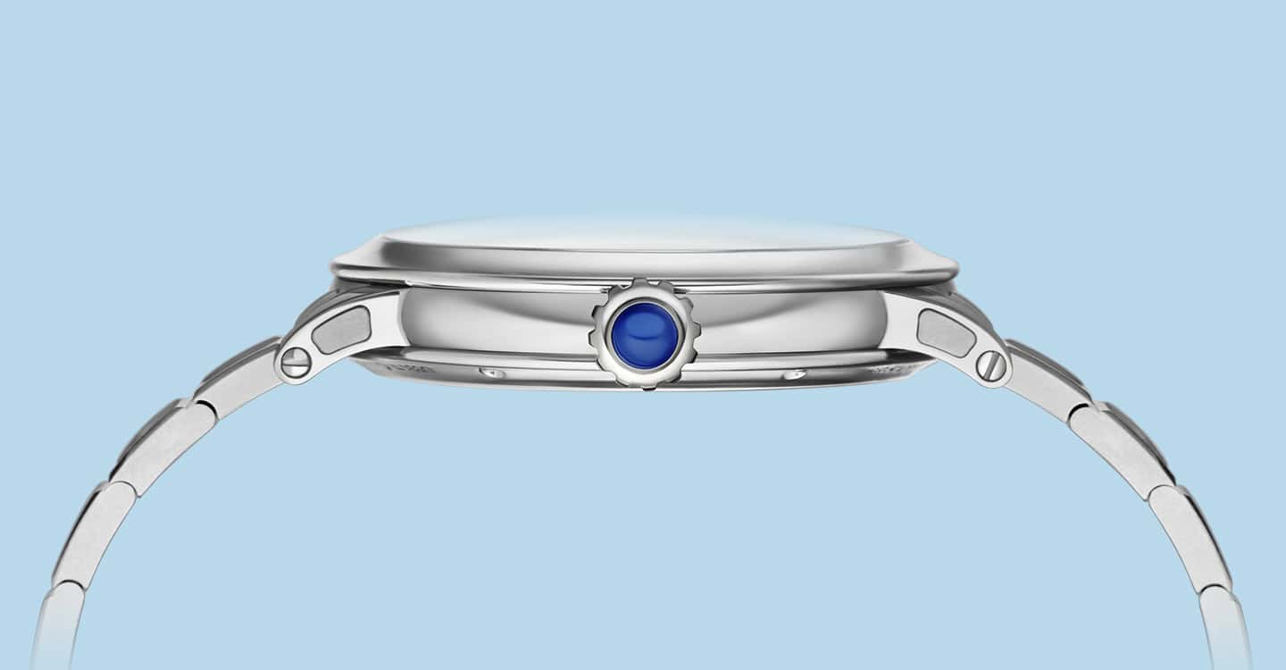 A sleek, elegant timepiece with a polished silver case and a blue cabochon crown, emphasizing crafts.