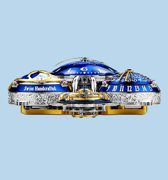 The image shows a highly detailed, luxurious timepiece with intricate craftsmanship and a vibrant bl.