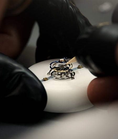 Hand assembling intricate timepiece components with precision tools.
