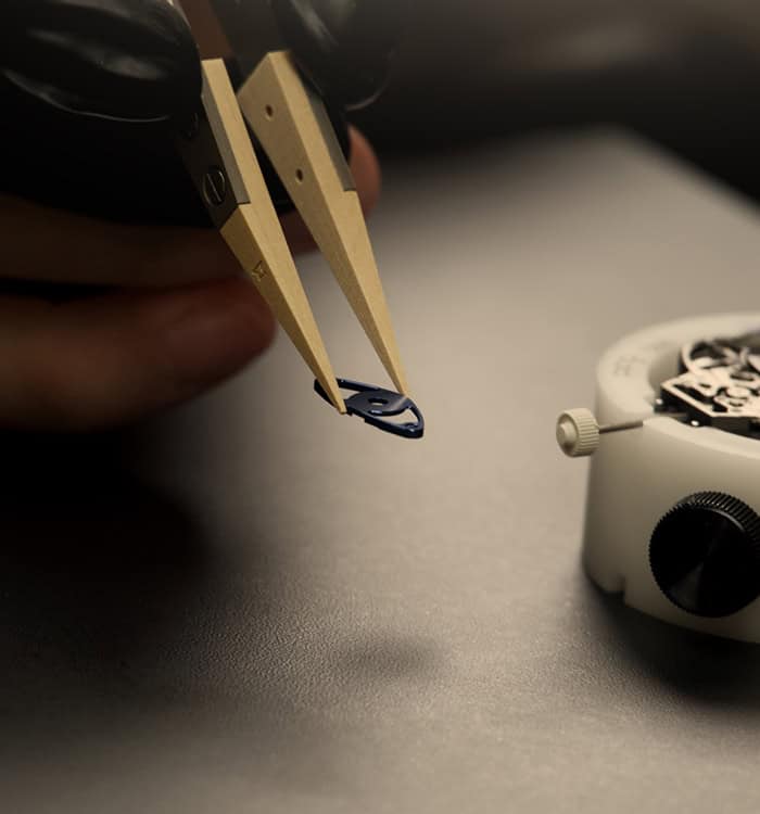 Precision assembly of a Fleurier Aperto 1 timepiece component with tweezers.