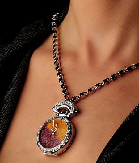 Elegant timepiece pendant with colorful dial and diamond accents on a silver chain.
