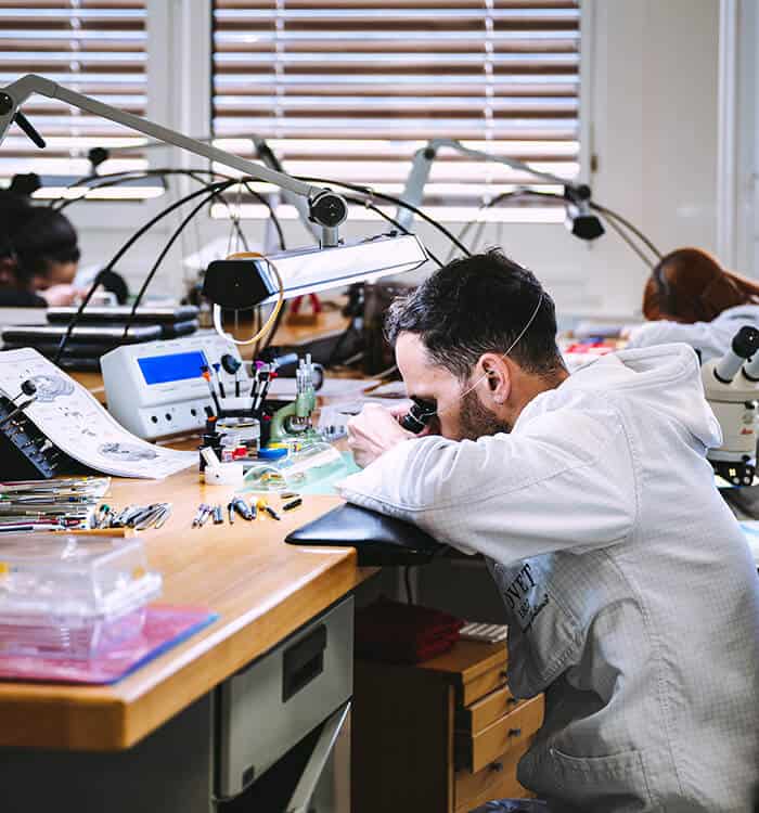 Intricate workspace with a watchmaker examining a timepiece under magnification in Fleurier.