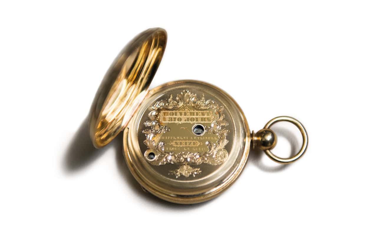 Vintage gold pocket timepiece with intricate engravings and open cover.