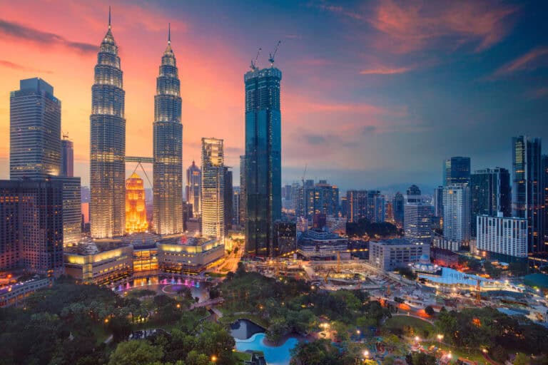Iconic Kuala Lumpur skyline with Petronas Towers and modern skyscrapers at sunset.