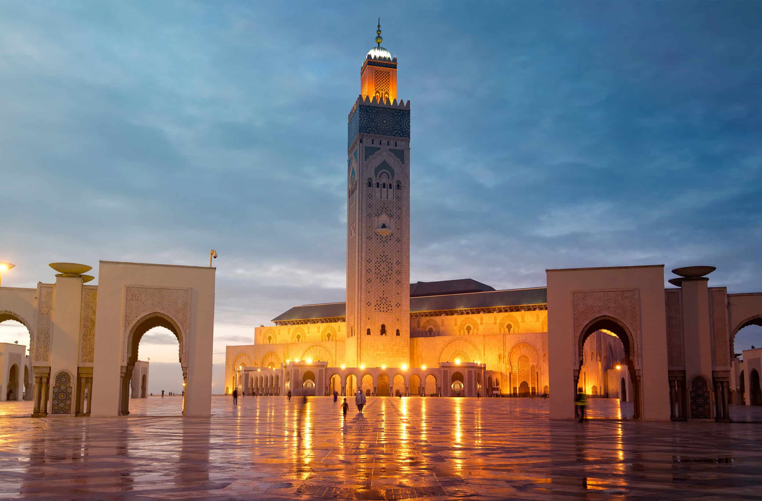 Elegant Moroccan mosque illuminated at dusk, showcasing intricate architecture and a towering minare.
