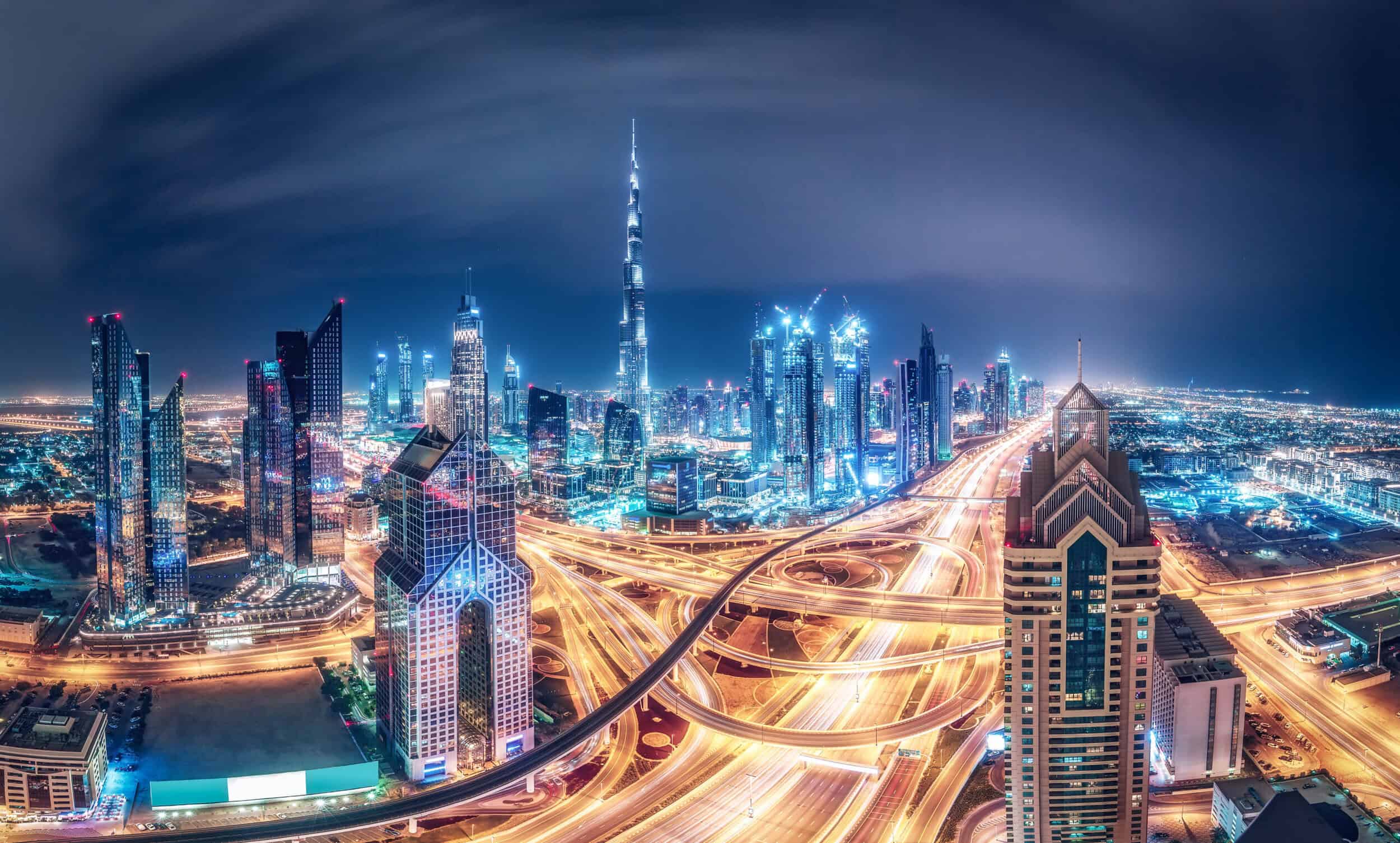 A stunning nighttime view of Dubai's skyline featuring illuminated skyscrapers and vibrant city ligh.