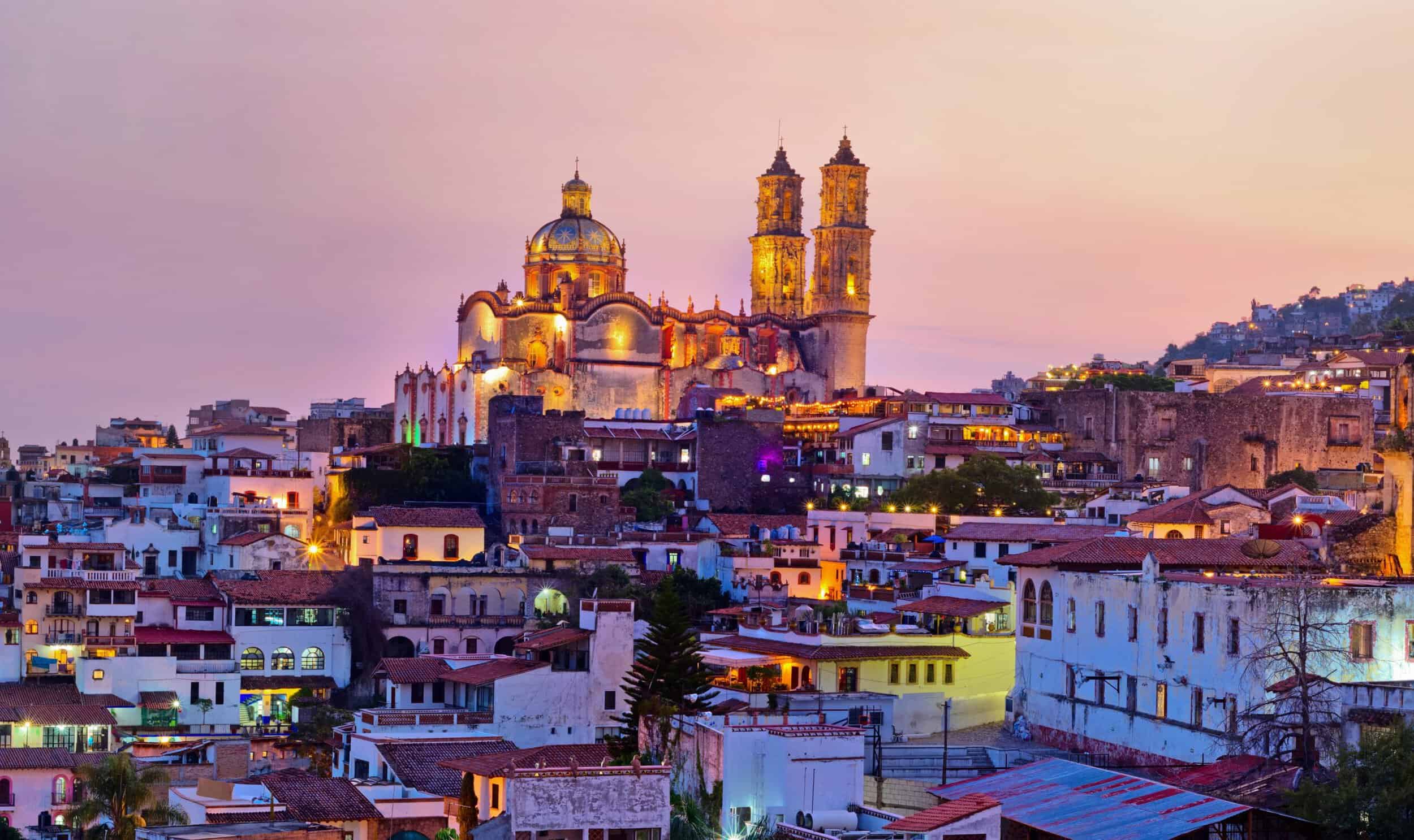 A stunning view of a historic cityscape with a prominent cathedral illuminated at sunset, emphasizin.