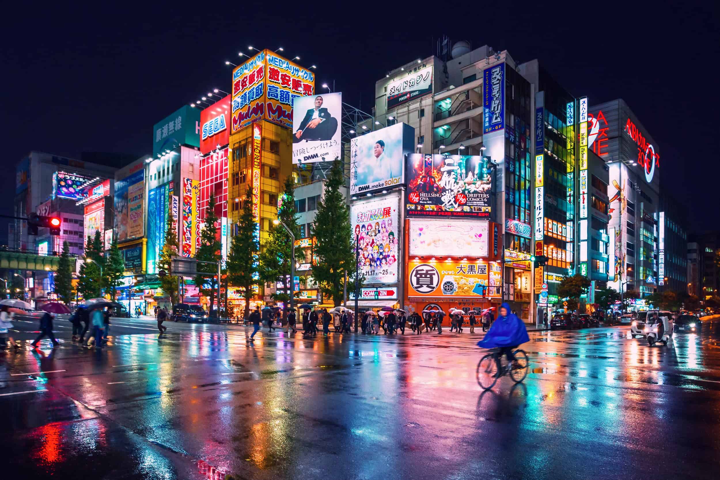 A vibrant Tokyo cityscape illuminated with colorful digital billboards and neon lights at night.
