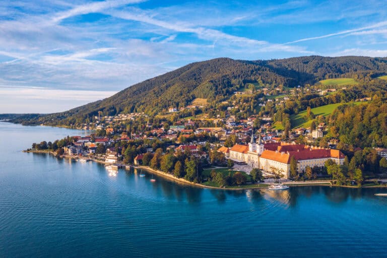A stunning aerial view of a lakeside town nestled among green hills under a blue sky, showcasing scene.