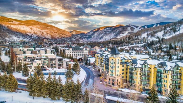 A stunning winter landscape of a mountain town with colorful buildings and snow-covered trees.
