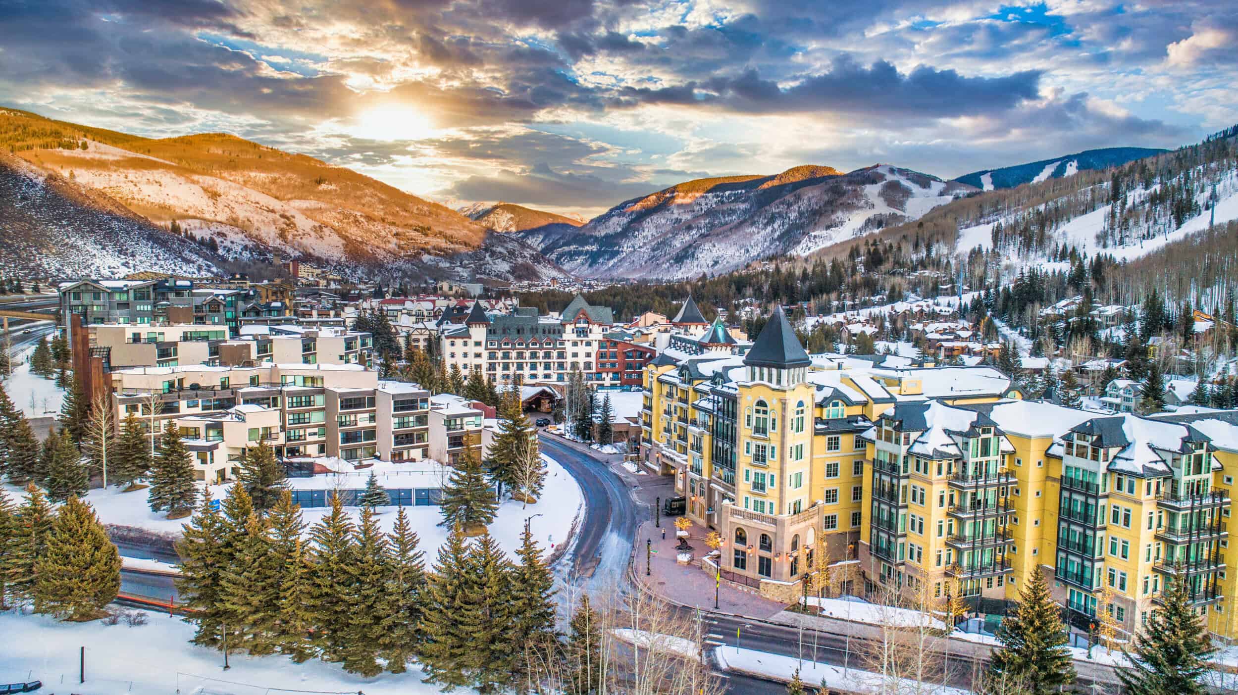 A stunning winter landscape of a mountain town with colorful buildings and snow-covered trees.