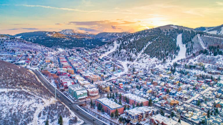 Scenic winter mountain town with colorful buildings and snow-covered slopes at sunset.