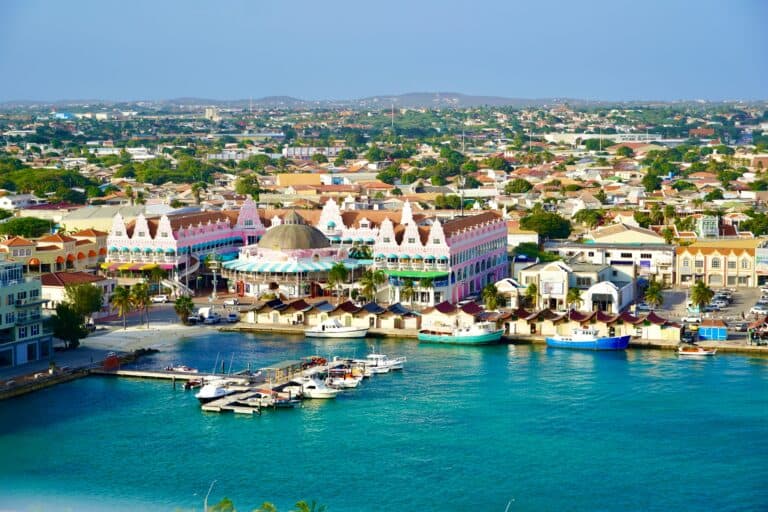 A colorful waterfront building with a pink and white facade, set against a cityscape under a clear b.