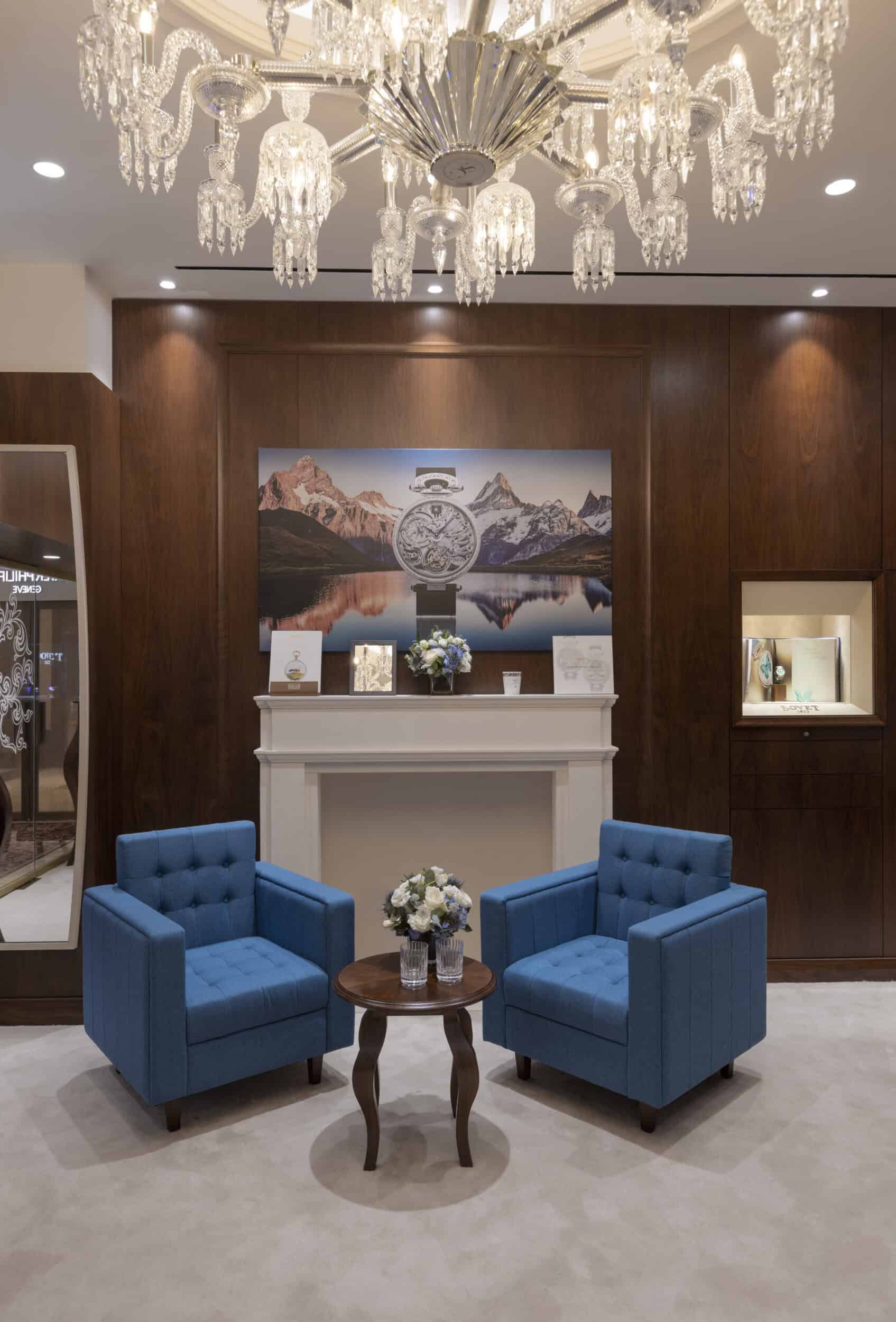Elegant interior with a chandelier, blue armchairs, and a scenic mountain painting, showcasing luxur.