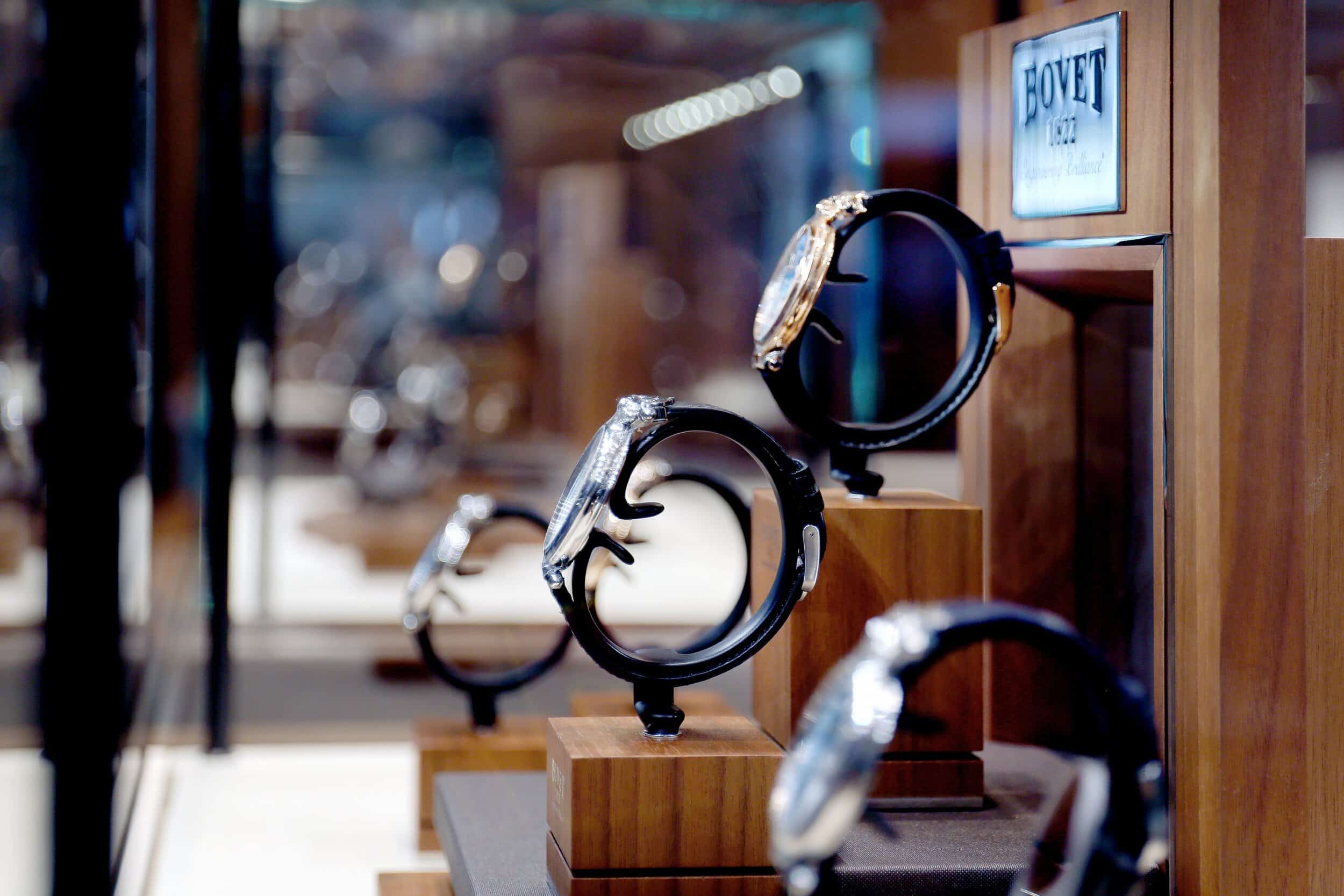 Elegant Bovet timepieces displayed on wooden stands in a luxury store setting.