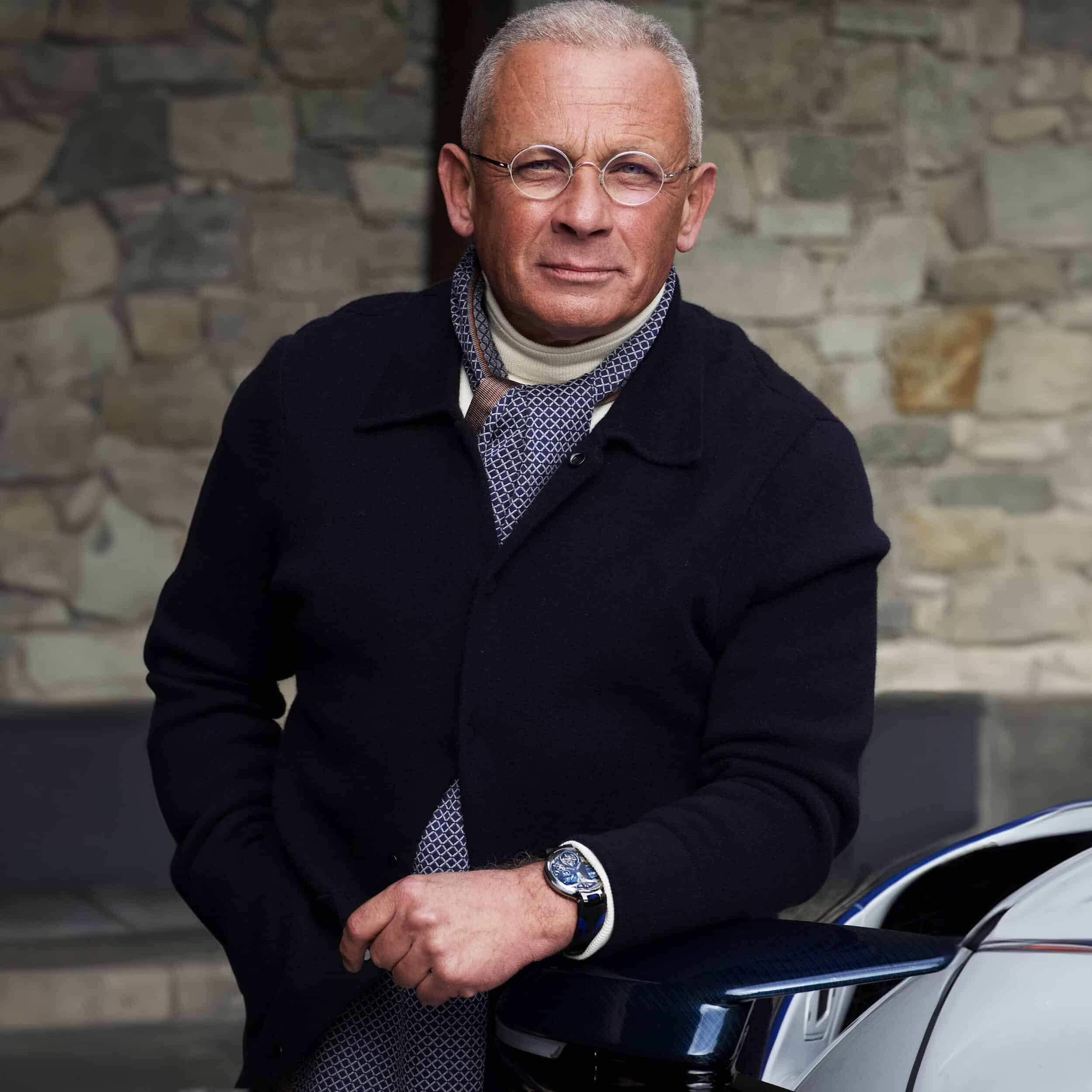 Elegant gentleman wearing Bovet timepiece with a stone wall background.