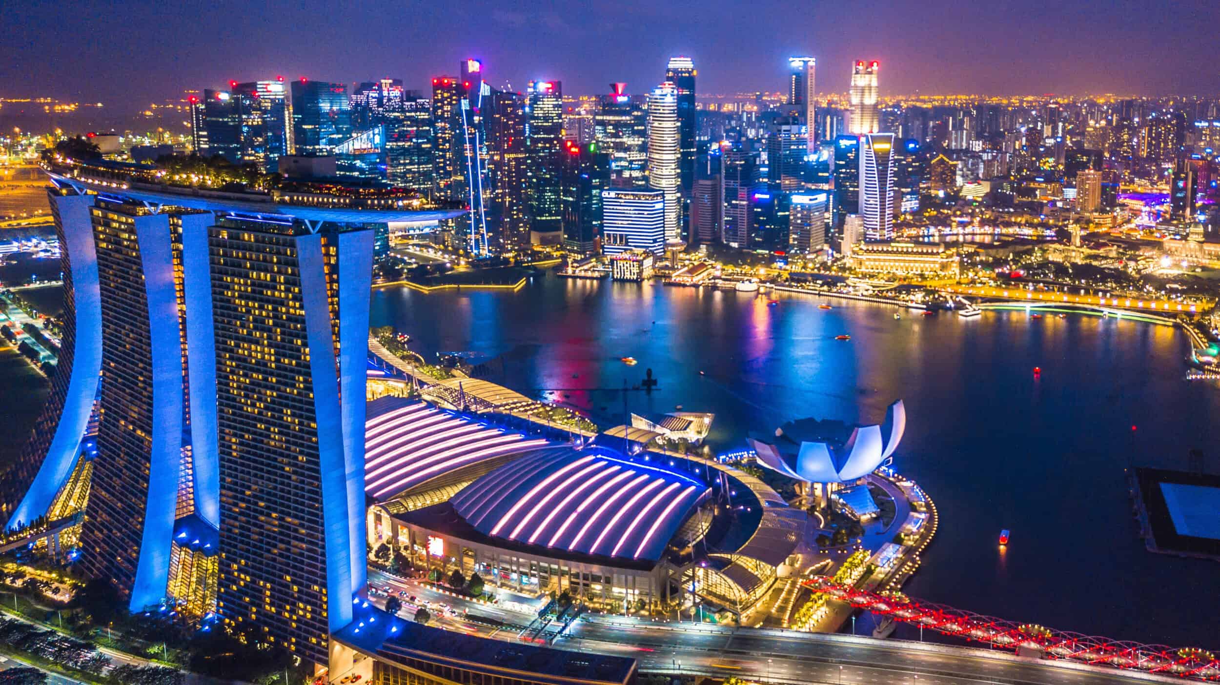 A stunning aerial view of Singapore's skyline illuminated at night, highlighting the city's vibrant.