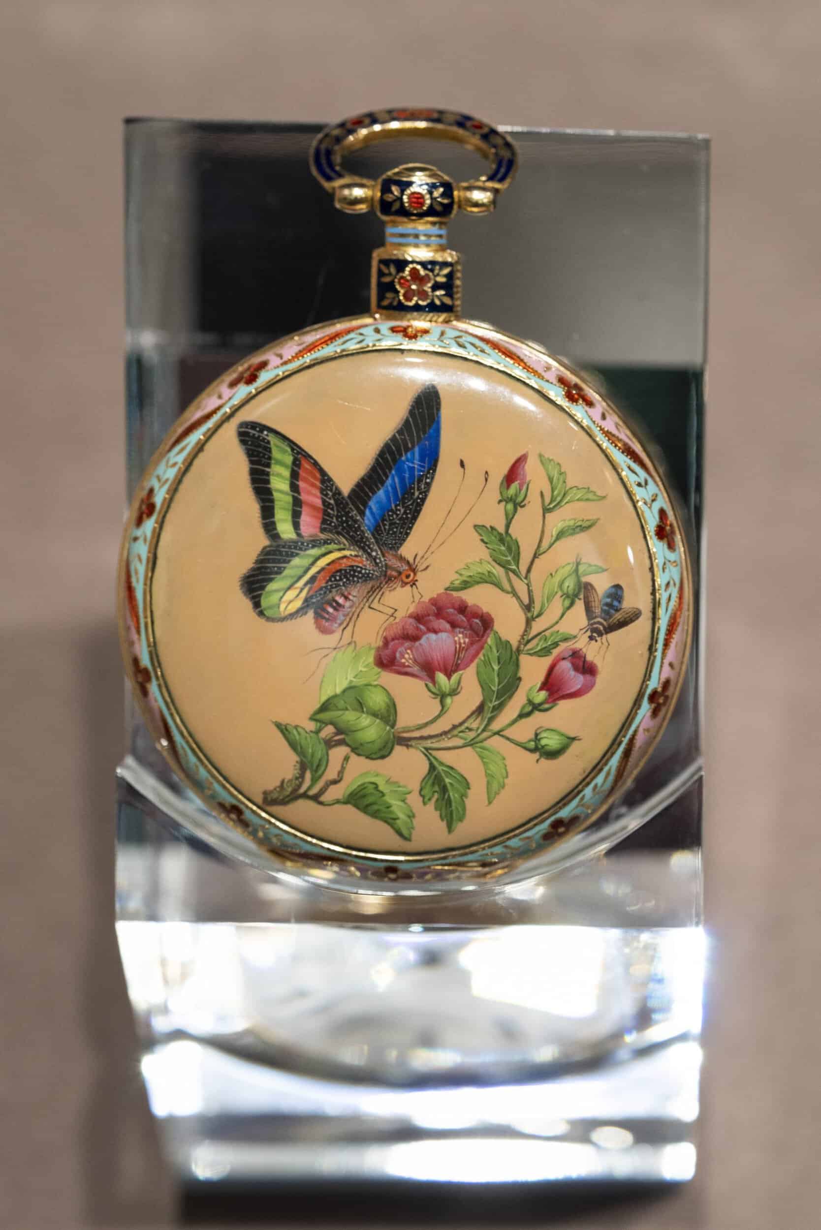 Exquisite enamel timepiece with butterfly and floral design, 200 years of craftsmanship.