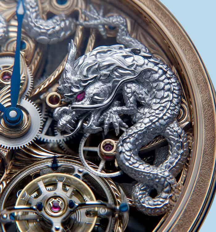 Intricate silver dragon sculpture on a luxurious gold and steel timepiece with visible gears and mec.