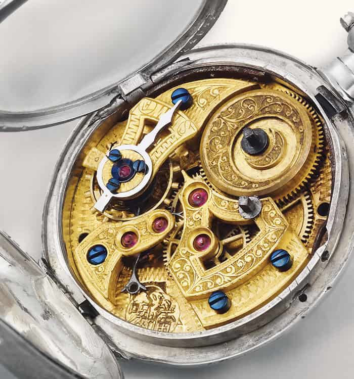 A detailed view of a vintage timepiece movement showcasing intricate gold gears and components.