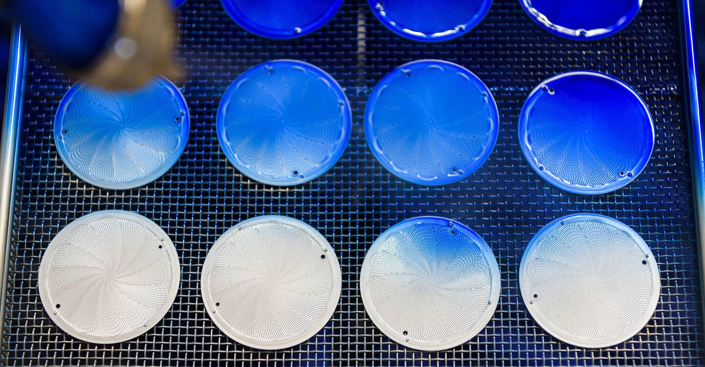 Polished blue and white ceramic components for luxury timepieces in a manufacturing process.